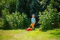 Happy small boy help with gardening with his lawn mower Royalty Free Stock Photo