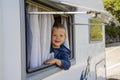 Happy small boy looking through the RV`s window parked along the road Royalty Free Stock Photo