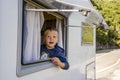 Happy small boy looking through the RV`s window parked along the road Royalty Free Stock Photo