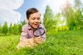 Happy small boy searches with magnifier and laying