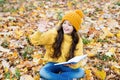 Happy small child with school book give salute with hand sitting on autumn leaves outdoors, literature Royalty Free Stock Photo