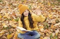 Happy small child with school book give salute with hand sitting on autumn leaves outdoors, literature Royalty Free Stock Photo