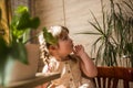 A cute baby girl takes care of houseplants. Girl watering and spraying indoor plants at home Royalty Free Stock Photo