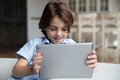 Happy small cute kid boy using digital computer tablet. Royalty Free Stock Photo