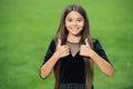 Happy small girl child with long hair and beauty look wear fashion dress showing thumbs ups hands gesture green grass Royalty Free Stock Photo