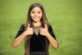 Happy small girl child with long hair and beauty look wear fashion dress showing thumbs ups hands gesture green grass Royalty Free Stock Photo