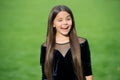 Happy small girl child with long hair in fashion wear smile with winking face green grass sunny summer outdoors