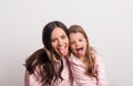 A small girl and her mother sticking tongues out in a studio.