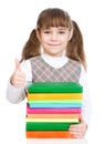 Happy small girl with pile books showing thumbs up. isolated