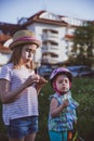 Happy small girls sisters blowing dandelion flower in the sity. One girl in a helmet