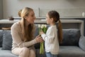 Happy small kid giving flowers to mum. Royalty Free Stock Photo