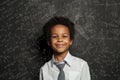 Happy smart black child student on blackboard background with science and maths formulas