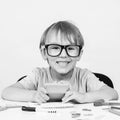 Happy smart boy in big glasses, sits at desk, looking to camera. Education. Kids idea. Genius. Back to school. Funny child in glas Royalty Free Stock Photo