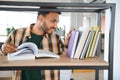 Happy smart indian or arabian guy, mixed race male, university student, stands in the library against the background of Royalty Free Stock Photo