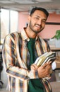 Happy smart indian or arabian guy, mixed race male, university student, stands in the library against the background of Royalty Free Stock Photo