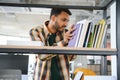 Happy smart indian or arabian guy, mixed race male, university student, stands in the library against the background of Royalty Free Stock Photo