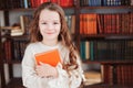 happy smart schoolgirl reading books in library or at home Royalty Free Stock Photo