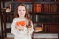 Happy smart schoolgirl reading books in library or at home Royalty Free Stock Photo