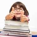 Happy smart young child with thumbs up leaning on books, indoor Royalty Free Stock Photo