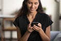 Happy smartphone user sitting on couch with gadget