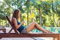 Happy smartphone woman relaxing near swimming pool. Beautiful girl using her mobile phone app 4g data to play songs while relaxing Royalty Free Stock Photo