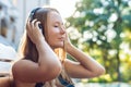 Happy smartphone woman relaxing near swimming pool listening with earbuds to streaming music. Beautiful girl using her mobile phon Royalty Free Stock Photo