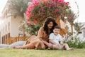 Happy smiing mother with son sitting on grass in park and smiling in camera. Parenting, family, children development Royalty Free Stock Photo