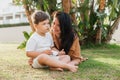 Happy smiing mother with son sitting on grass in park and smiling in camera. Parenting, family, children development Royalty Free Stock Photo