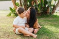 Happy smiing mother with son sitting on grass in park and smiling in camera. Parenting, family, children development Royalty Free Stock Photo