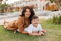 Happy smiing mother with son sitting on grass in park and smiling in camera. Parenting, family, children development Royalty Free Stock Photo