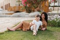 Happy smiing mother with son sitting on grass in park and smiling in camera. Parenting, family, children development Royalty Free Stock Photo