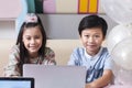 Happy smile Asean girl and boy using laptop computer togeter to study online e-learning together from living room decorate Royalty Free Stock Photo