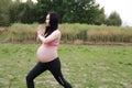 Happy smile Asian Chinese pregnant woman in yoga dress do meditation in nature sit on grass lawn live balanced healthy  life Royalty Free Stock Photo