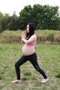 Happy smile Asian Chinese pregnant woman in yoga dress do meditation in nature sit on grass lawn live balanced healthy  life Royalty Free Stock Photo