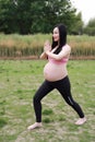 Happy smile Asian Chinese pregnant woman in yoga dress do meditation in nature sit on grass lawn live balanced healthy  life Royalty Free Stock Photo