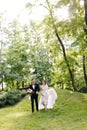 Happy smile bride and groom look at each other and running in the green garden. Wedding in the summer in the park. Happy Royalty Free Stock Photo