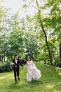 Happy smile bride and groom look at each other and running in the green garden. Wedding in the summer in the park. Happy Royalty Free Stock Photo