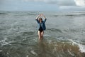 Happy smile brunette Woman wearing black swimsuit and denim jacket at ocean background enjoy walking in ocean, hands raised up Royalty Free Stock Photo
