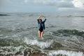 Happy smile brunette Woman wearing black swimsuit and denim jacket at ocean background enjoy walking in ocean, hands raised up Royalty Free Stock Photo