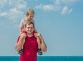Happy smile father hugs holds on shoulders boy male child stand blue lazur sea panorama skyline horizon sunshine day