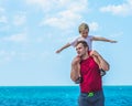 Happy smile father hugs holds on shoulders son boy male child stand blue lazur sea panorama skyline horizon in sunshine