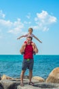 Happy smile father hugs holds on shoulders son boy male child stand blue lazur sea panorama skyline horizon in sunshine