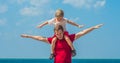 Happy smile father hugs holds on shoulders son boy male child stand blue lazur sea panorama skyline horizon in sunshine