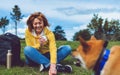 Happy smile girl holding in hands cup drink playing with red japanese dog shiba inu on green grass in outdoors nature park, young