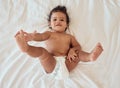 Happy, smile and portrait of a baby with a diaper relaxing on a bed in his bedroom or nursery. Happiness, health and Royalty Free Stock Photo