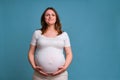 Happy smile on pregnant woman face, studio shot on blue background