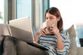 Happy smile young asian woman working with laptop and hold pen with notebook and sitting on sofa at home office, Selective focus Royalty Free Stock Photo