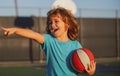 Happy smilin kid playing basketball, pointing showing gesture. Activity and sport for kids. Royalty Free Stock Photo