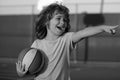 Happy smilin kid playing basketball, pointing showing gesture. Activity and sport for kids. Royalty Free Stock Photo