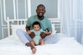 Happy smiling African american dad with baby son on bed at home cuddling and playing, happy family, father`s day Royalty Free Stock Photo